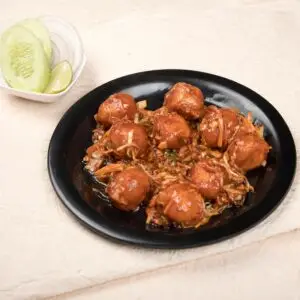 Tasty Manchurian balls served with cucumber, lime, and onions.